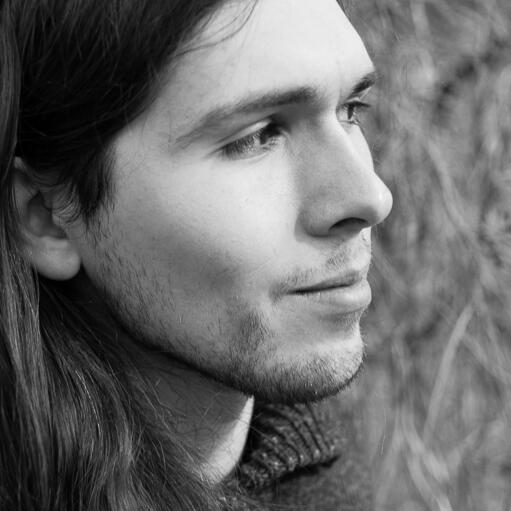 A greyscale photo of Sean, looking to the right, smiling slightly.